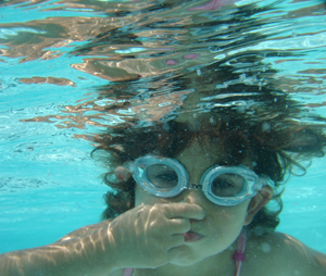 girl underwater holding her nose