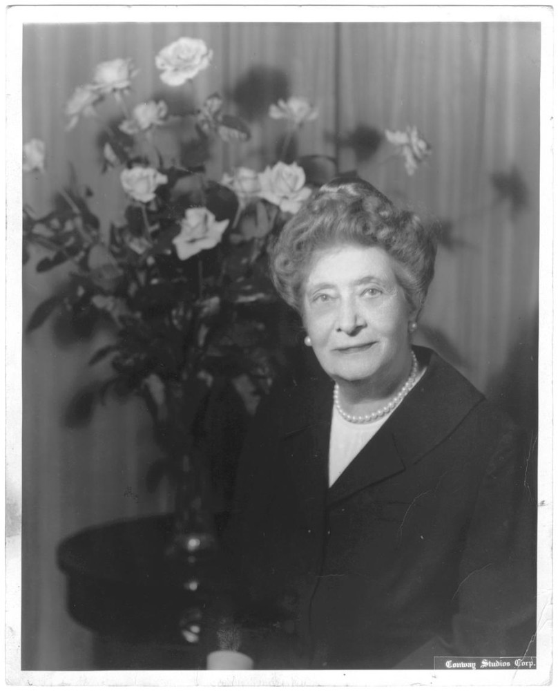 Ima Hogg seated in front of floral arrangement