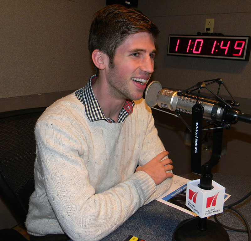 Daniel Barker speaking into a microphone at Houston Public Media studios