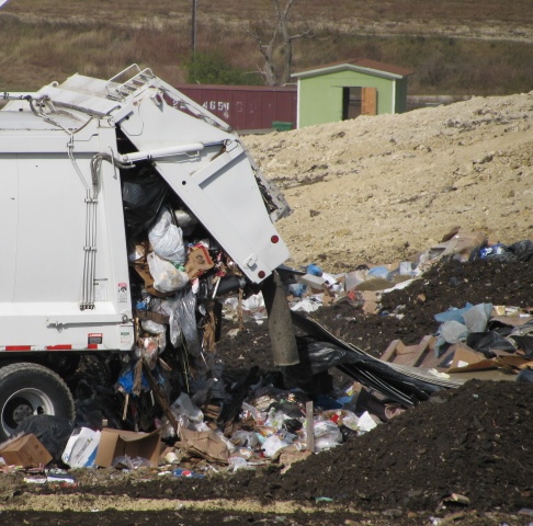trash truck dumping trash into a landfill