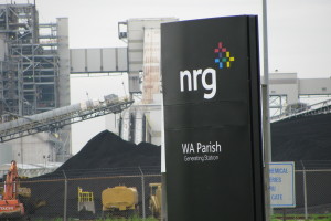 photo of NRG sign with coal mounds in background