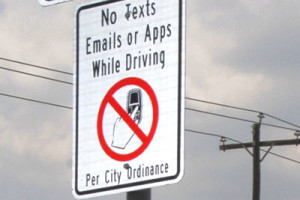 The sign reads, "No texts, emails or apps while driving per city ordinance"