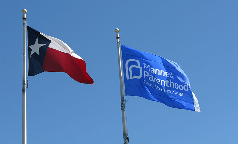 state of Texas Flag waving next to a Planned Parenthood flag