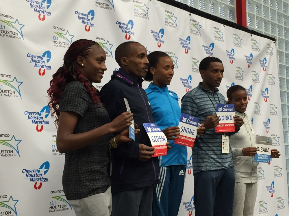 Runners pose for a picture holding their marathon bibs. 