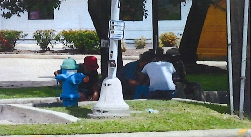 A group of people sit at one of the comers near the intersection of South Post Oak and West Bellfort.