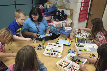 Anna Marie McClanahan (center) helps children write stories by using Legos to create scenes.