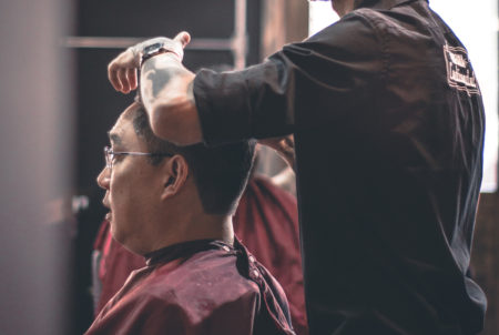 A hair stylist cuts a man's hair.