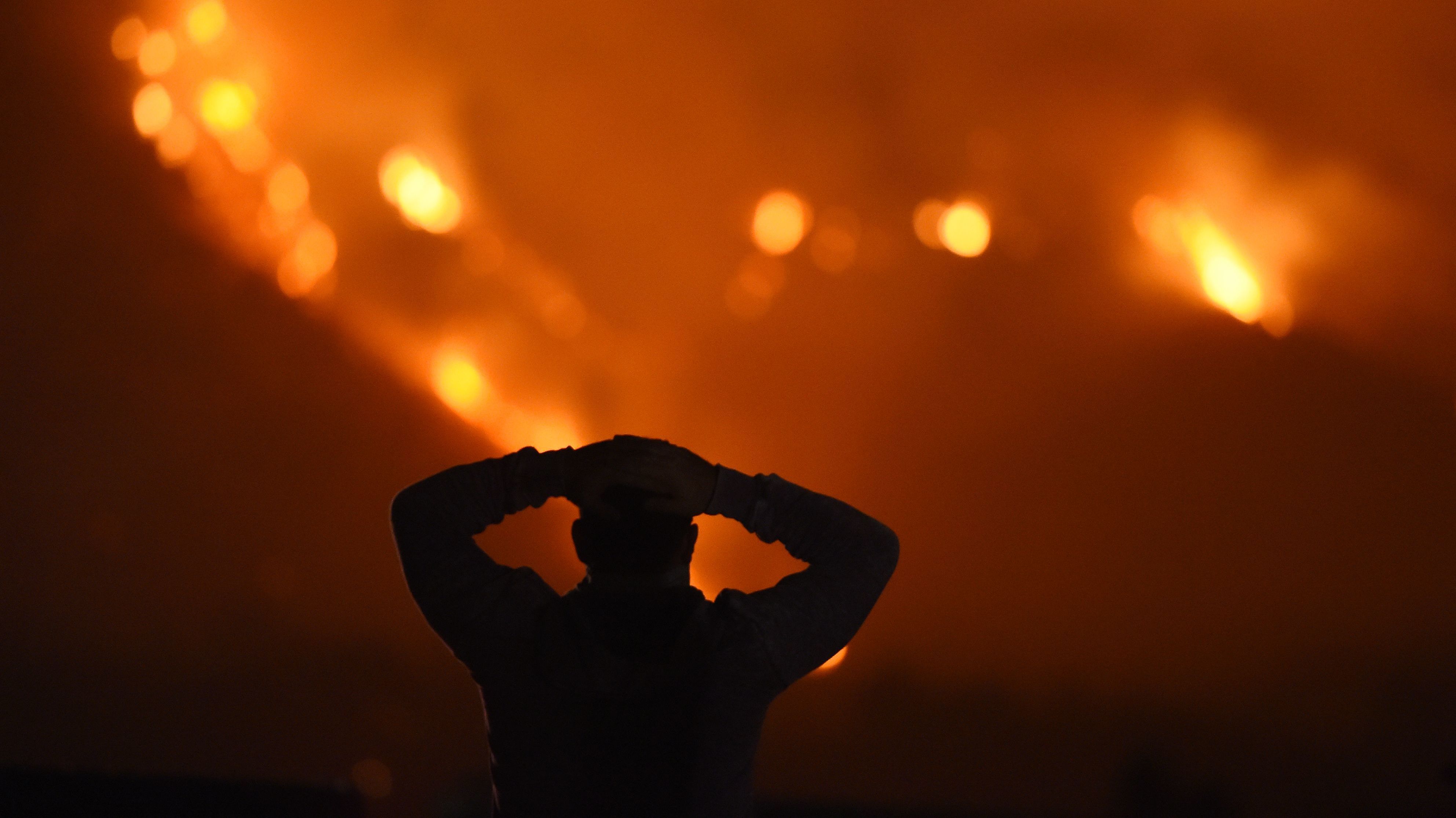 A man watches the Thomas Fire in the hills above Carpinteria, California.