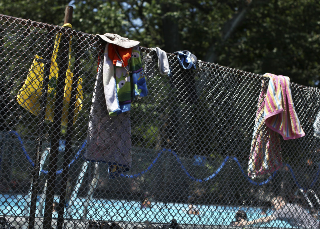 Swimming towels hang from a fence outside a pool at Tompkins Square Park in New York July 8, 2012. A blistering heat wave finally showed signs of letting up across the U.S. Midwest and Northeast on Sunday, with more moderate temperatures bringing relief to overheated residents from Chicago to New York, according to meteorologists.  
REUTERS/Shannon Stapleton (UNITED STATES - Tags: ENVIRONMENT SOCIETY) - GM1E87907FO01