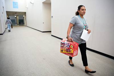 Tiffany Robinson, a science instructional specialist, carries a box of snacks to entice students to stay for an after-school tutorial on April 19, 2018. 