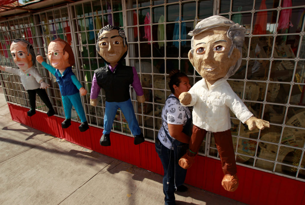 A woman hangs up pinatas for sale depicting Mexican presidential candidates outside a pinata store in Ciudad Juarez. 