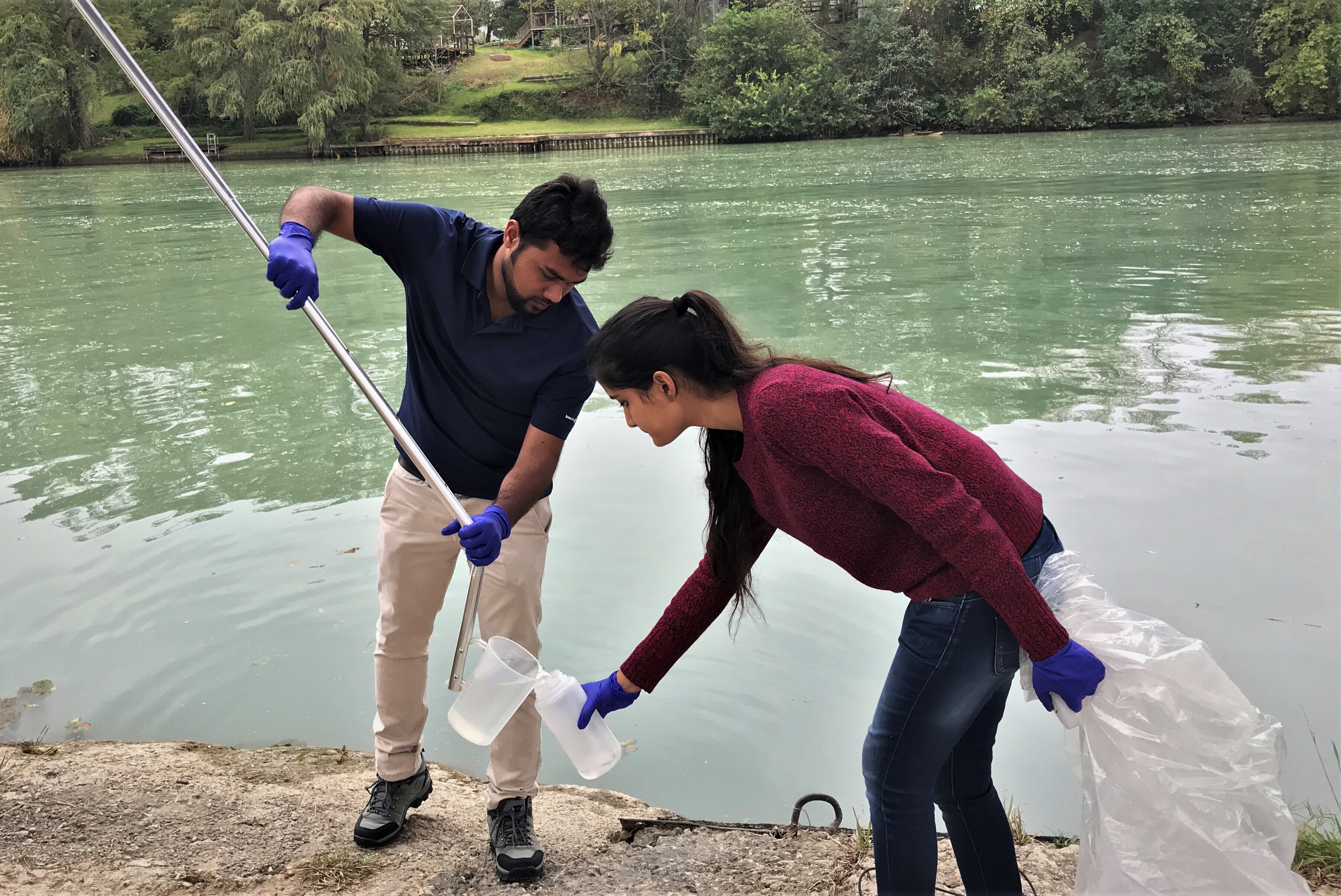UTSA graduate students Tanvir Pasha (left) and Indrani Gupta (right) collect samples of water to study.