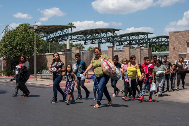 Central American asylum seekers walk to the nearby Catholic Charities Humanitarian Respite Center after being dropped off at the McAllen bus station, on August 2, 2018.  