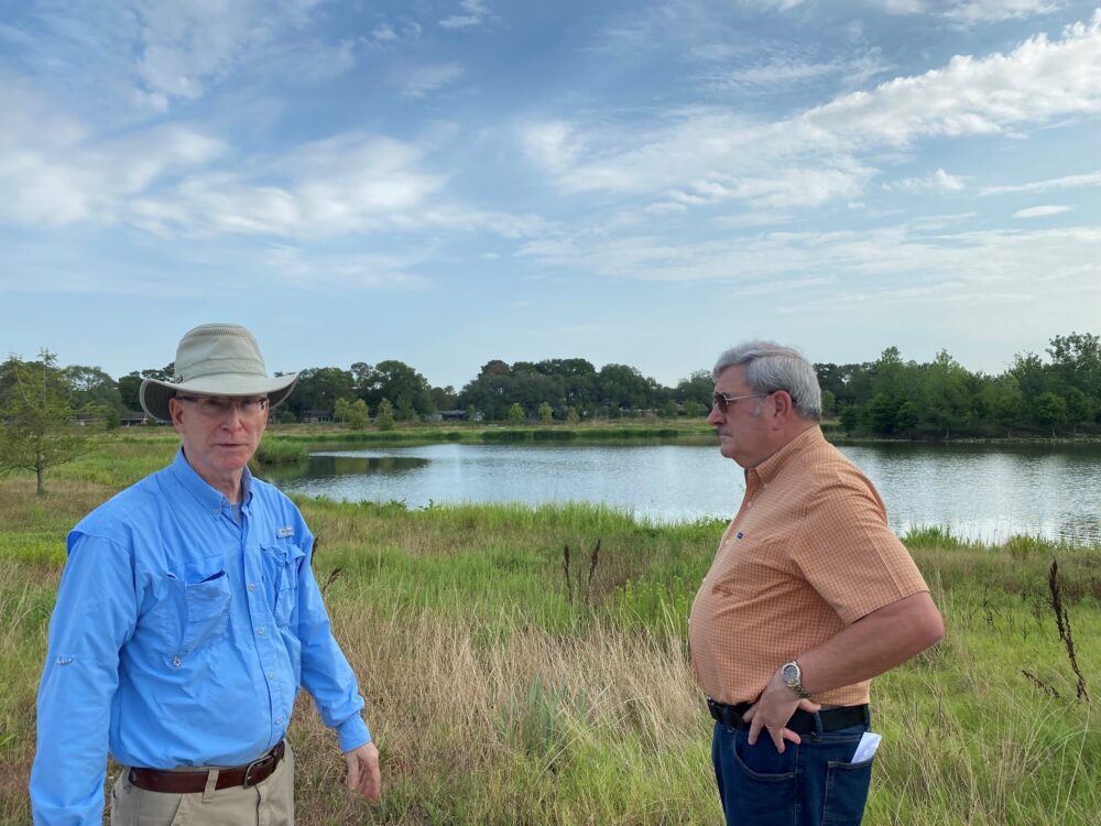 David Sharp (left) & John Branch stand in front of one of the retention ponds at Exploration Green. Each pond can hold up to 100 million gallons of stormwater. They also serve as a habitat for wildlife and a public space with walking trails.