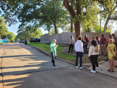 Researchers stand on the sidewalk of a tree-lined residential street to observe how the pavement buckled and ground subsided along a fault line in Spring Break