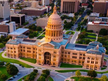 The Texas State Capitol building in Austin lit by warm sunlight, seen from above.